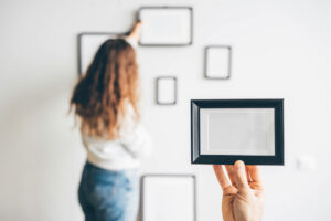 couple hanging picture frame on wall in new house