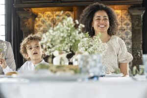 A smiling woman and a young child are seated at a wedding reception table