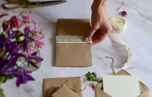 handmade invitation with person's hand putting ribbon on envelope