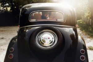 bride and groom sitting in classic, vintage car