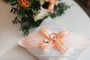 gold wedding rings on small pillow with pink bow and pearls