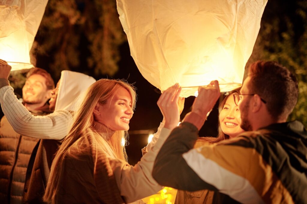 friends and family smiling while releasing lanterns into the sky