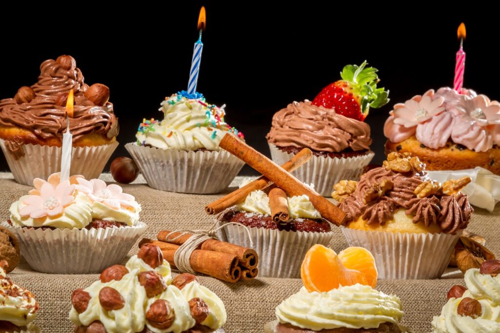 Closeup birthday muffins with cream, fruits and nuts