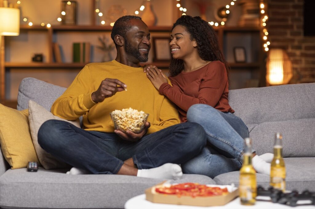 couple on couch eating popcorn and enjoying a movie